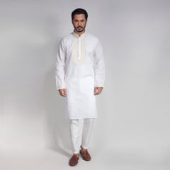 Man wearing a white kurta with embroidery on a plain background