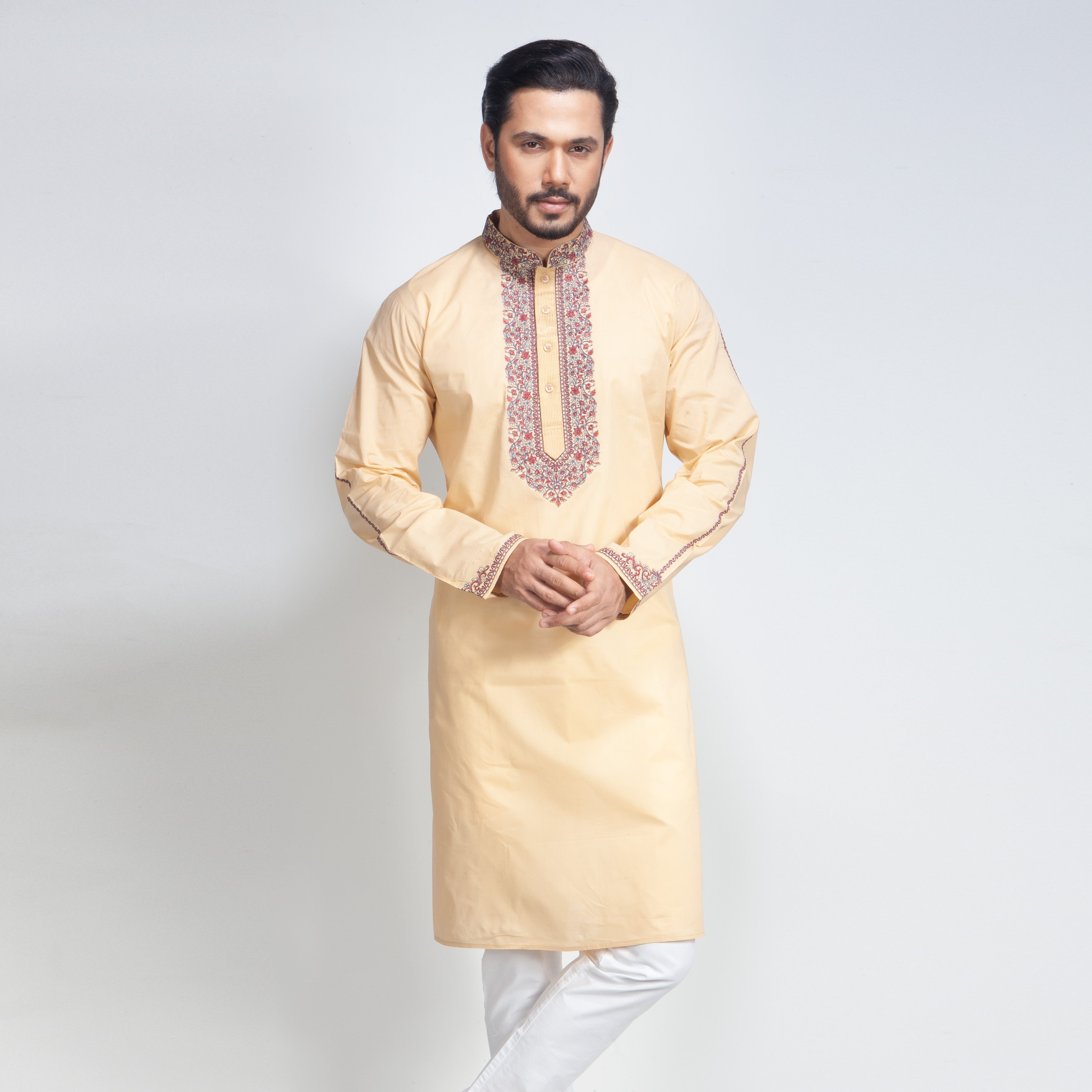 Man wearing a beige kurta with white pants on a light gray background
