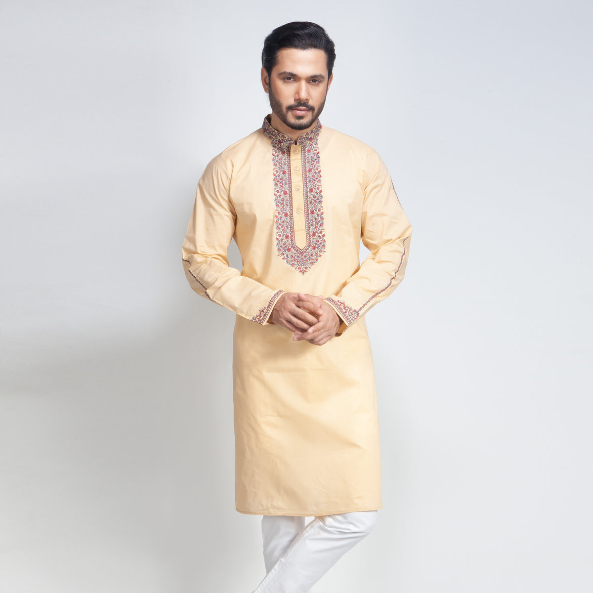 Man wearing a beige kurta with white pants on a light gray background