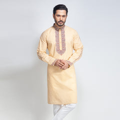Man wearing a beige kurta with white pants on a light gray background