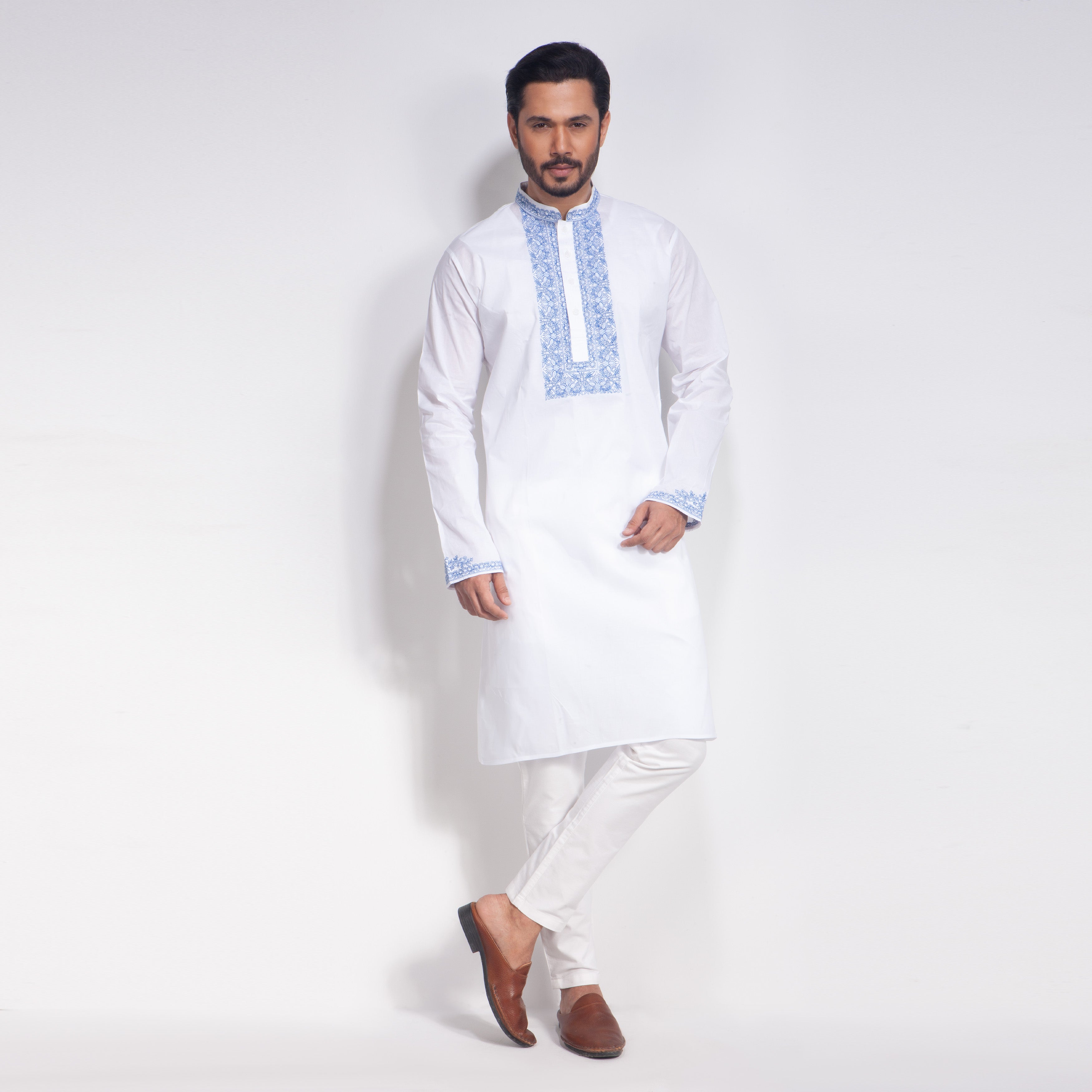 Man wearing a white panjabi with blue embroidery on a white background